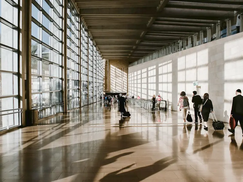 Travellers with suitcases in a sunlit airport terminal